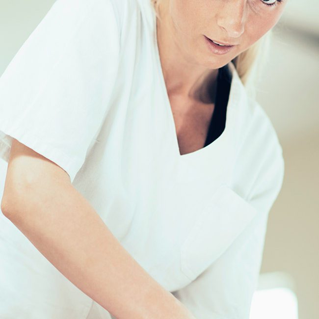 A woman in white shirt holding something on top of table.