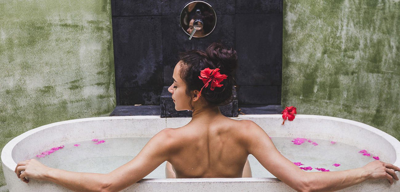 A woman sitting in the tub with her hair hanging down.