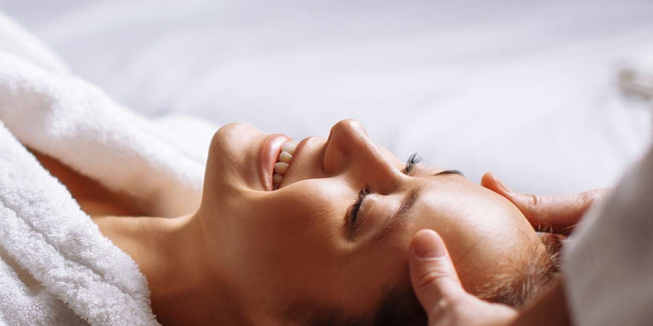 A person laying on top of a bed with their eyes closed.