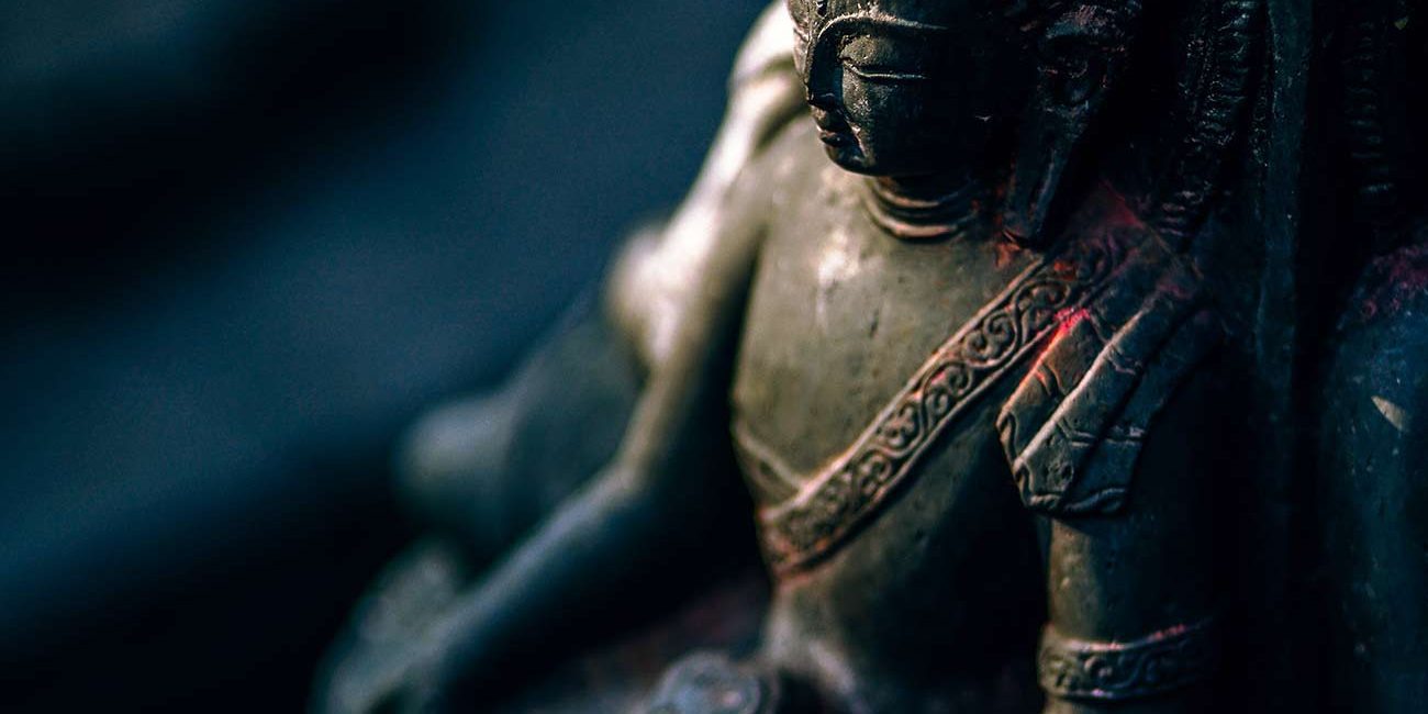 A statue of buddha sitting in the middle of a forest.