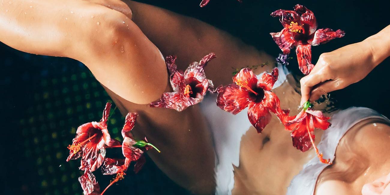 A woman is sitting on the ground with flowers in her hair.