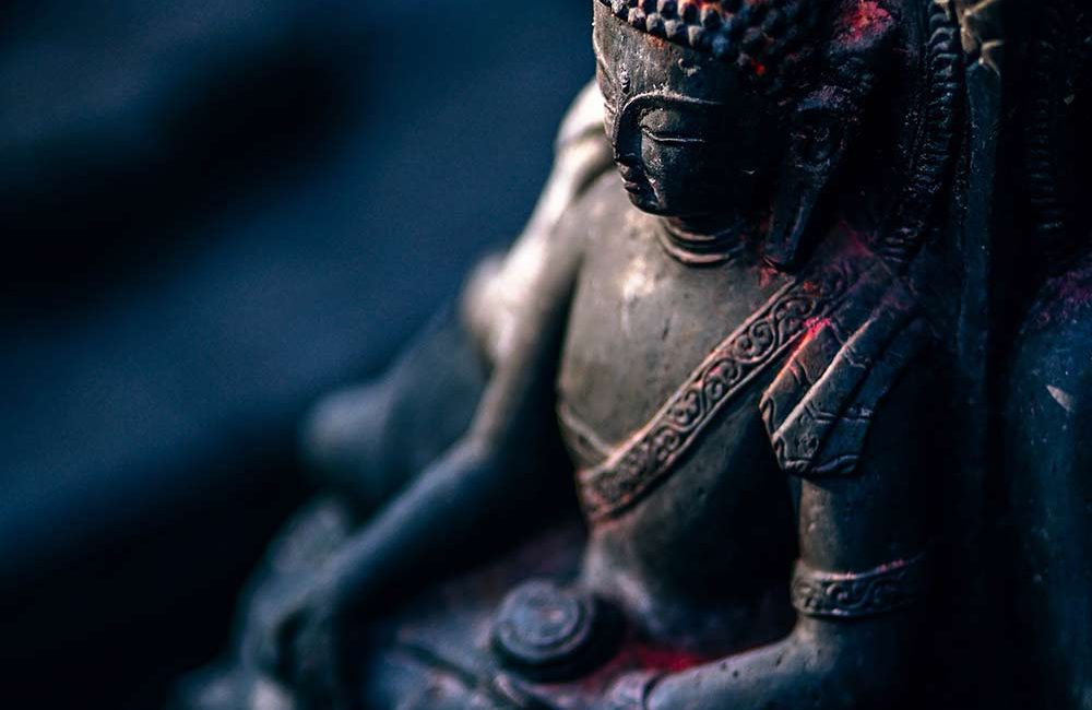 A statue of buddha sitting in the middle of a forest.