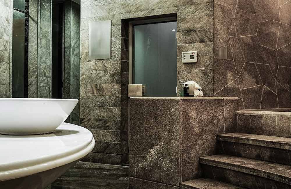 A bathroom with marble walls and floors, and a sink.