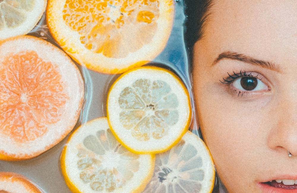 A woman with oranges and lemons in front of her face.