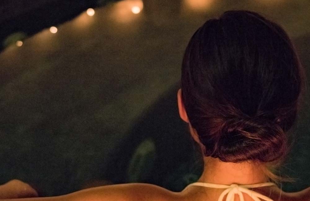 A woman sitting in the tub with her back turned.