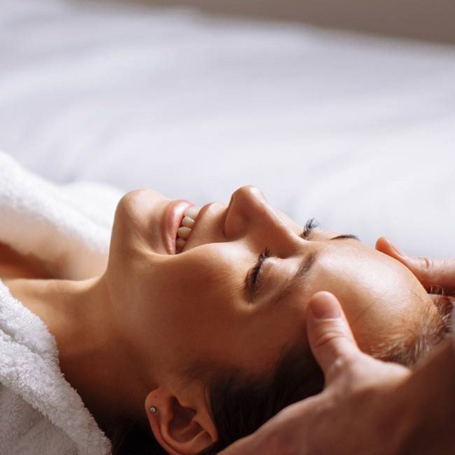 A person laying on their stomach with hands touching her face.